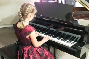 Young girl playing the piano at her first piano recital.